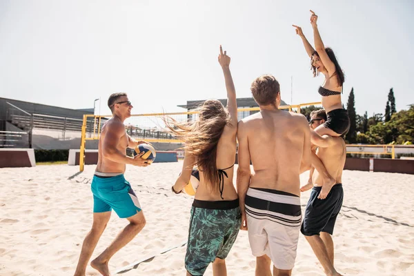 Grupo de amigos caminhando no campo de vôlei de praia na manhã ensolarada. — Fotografia de Stock