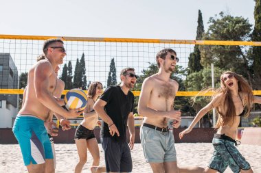 Bir grup genç arkadaş voleybol sahasında yürüyor..