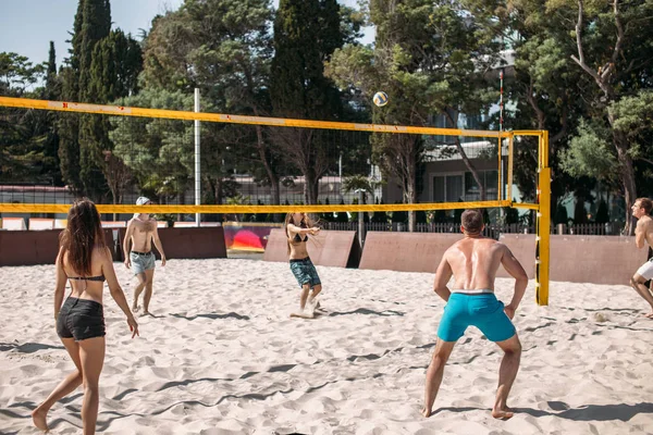 Grupa młodych białych przyjaciół gra w siatkówkę na plaży na wakacjach — Zdjęcie stockowe