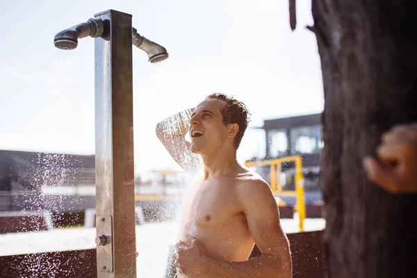 Stilig ung topless kaukasier man tar en utomhusdusch på stranden. — Stockfoto