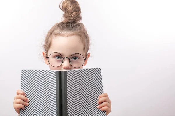 Belle fille intelligente avec les yeux verts dans des lunettes rondes tenant un livre — Photo