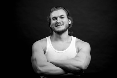 siyah beyaz fotoğraf. Kollarını kavuşturup kameraya bakan güçlü bir adam..