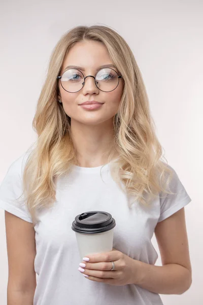 Хорошо выглядящая модель с кофе смотрит на камеру — стоковое фото