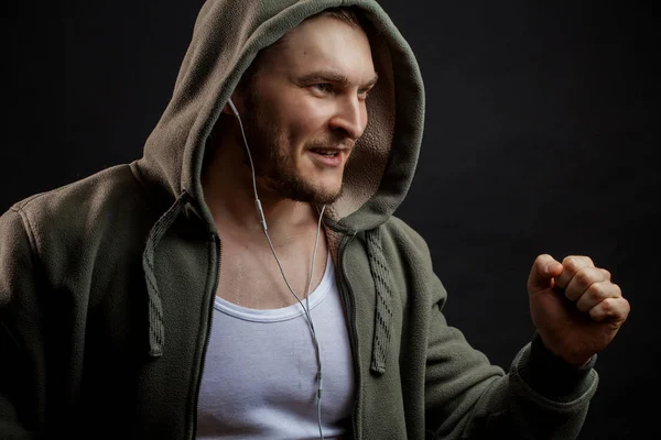 Homem de capuz verde ouvindo música enquanto jogging — Fotografia de Stock