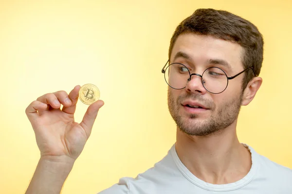 Ein neugieriger gutaussehender Kerl mit einer goldenen Münze — Stockfoto