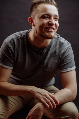 Tişörtlü gülen genç adam, pantolonu bacaklarının üzerinde.