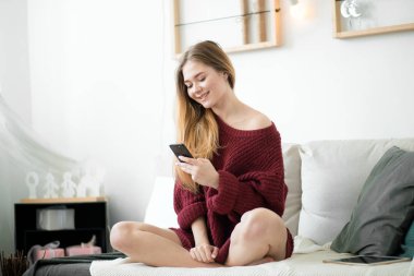 oturma odasında Smartphone kullanan neşeli kız