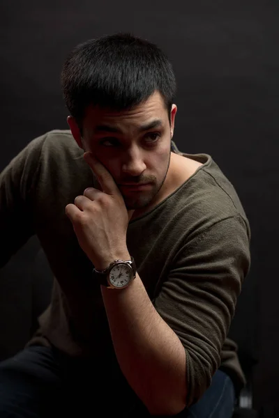 Close up portrait. a thoughtful attractive man sitting in front of the blavk wall — Stock Photo, Image