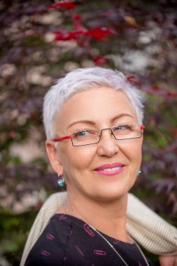 Kısa saç stili ve parlak makyajlı olgun bir kadının kesilmiş fotoğrafını çek.