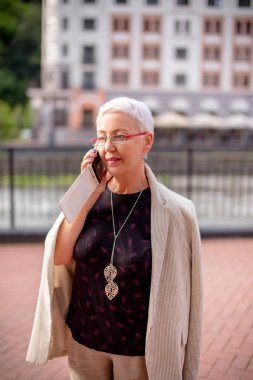 Çekici bir kadın sokakta akıllı bir telefonla konuşuyor.