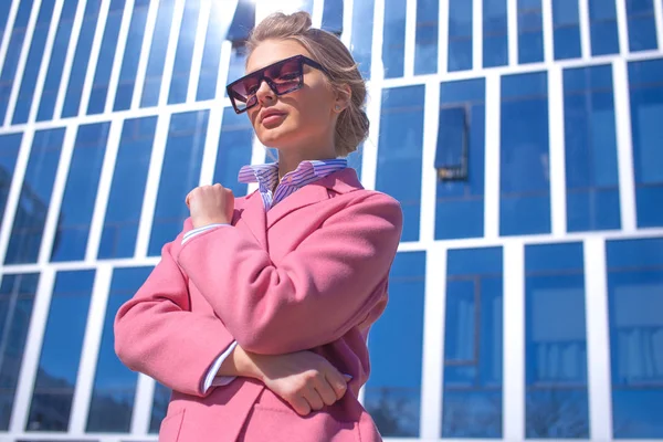 Modelo joven en abrigo rosa está en frente del magnífico edificio —  Fotos de Stock