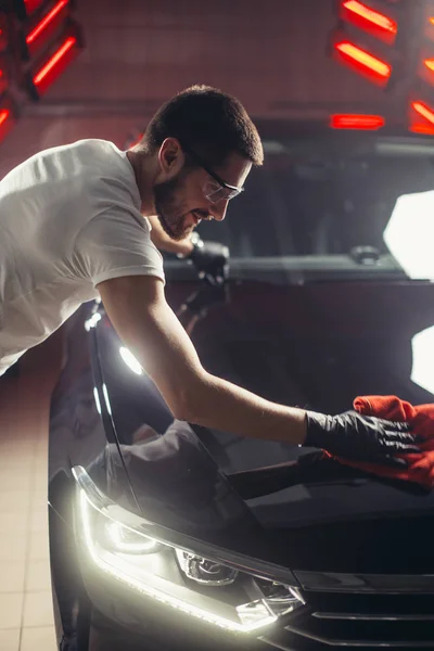 Car detailing - the man holds the microfiber in hand and polishes the car — Stock Photo, Image