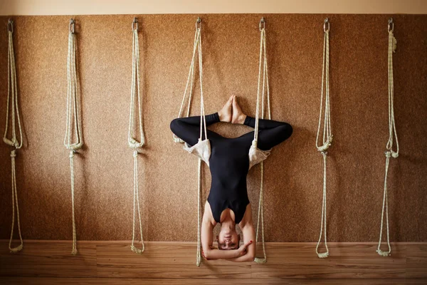 Pleasant gifted gymnast is doing bound angle pose upside down on the ropes — Stock Photo, Image