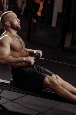 spor salonunda kapalı kürekçi üzerinde oturan yorgun sportif adam