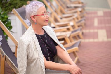 sokakta sandalyede oturan bir güzel, mutlu ve akıllı iş kadını.