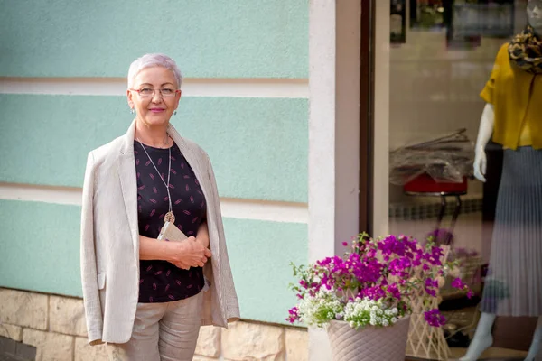 Awesome positiv kvinna som står bredvid butiken med trendiga kläder — Stockfoto
