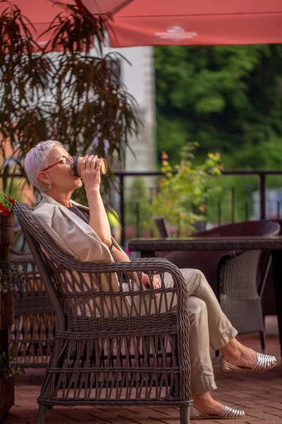 Moda mujer madura está bebiendo café en el sillón — Foto de Stock