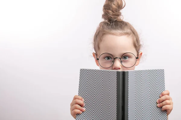 Petite fille agréable cachée derrière le livre — Photo