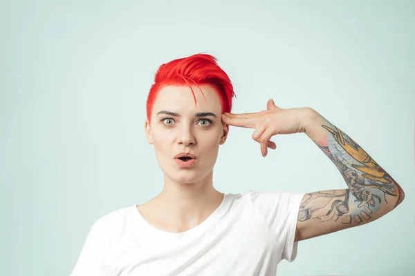 Confused and unhappy good looking girl keeping her hand on the head like a gun — Stock Photo, Image