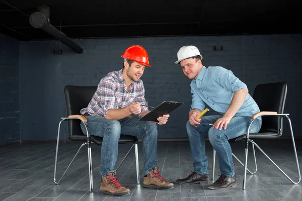 Zwei talentierte Arbeiter in Hardhats schauen sich die Dokumente an — Stockfoto