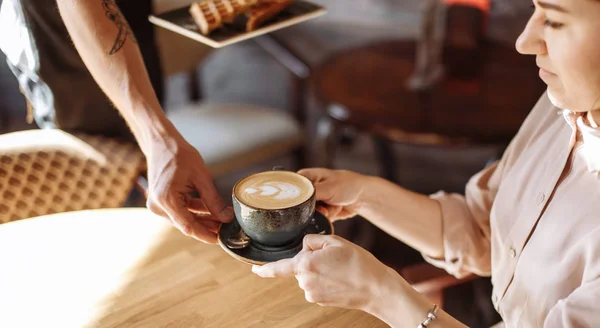 Een ober is het geven van een kopje latte met een vrouw in het café — Stockfoto