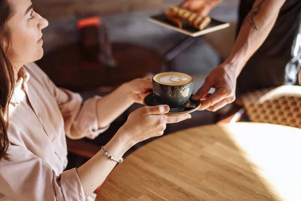 En trevlig kvinna är att tacka en servitör för en kopp latte — Stockfoto