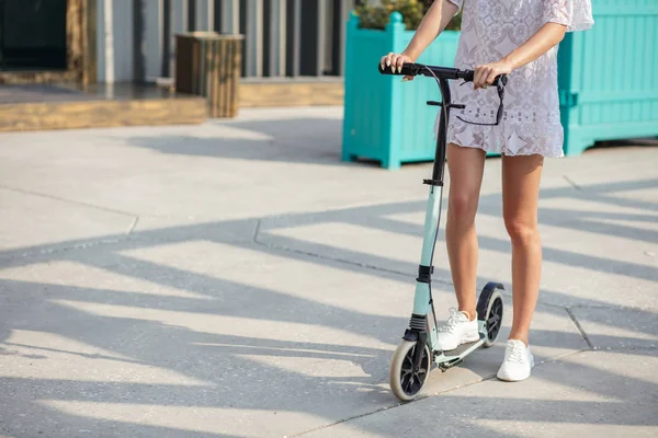 夏天，女人的腿骑着蓝色的踢踏车在路上 — 图库照片