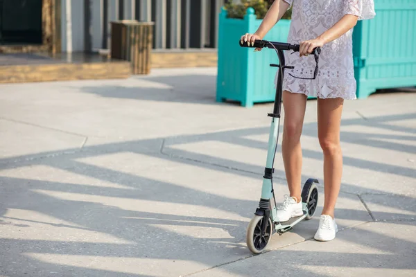 Close-up vrouw benen op blauwe kick scooter op weg in de zomer dag — Stockfoto