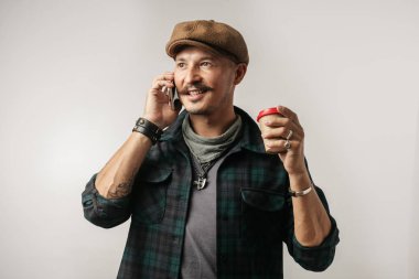 Deri ustası akıllı telefon kullanıyor ve elinde bir fincan kahve tutuyor.