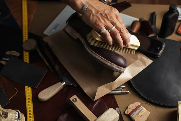 Entretien des chaussures en cuir, gros plan des mains cultivées du cordonnier frottant les bottes — Photo