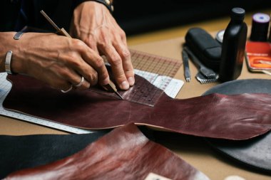 Close up of skinner craftsman working with natural leather using craft tools. clipart