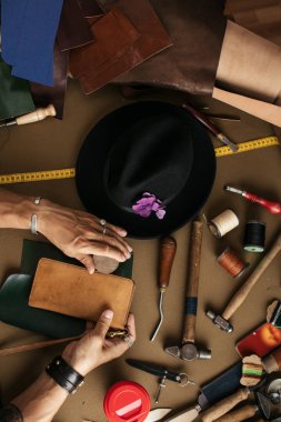 Atölyede deri numune ve çekiçle çalışan bir kunduracıya yaklaş.