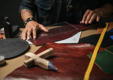 Bir atölyede deri tekstil ve çekiçle çalışan bir kunduracının önünde.