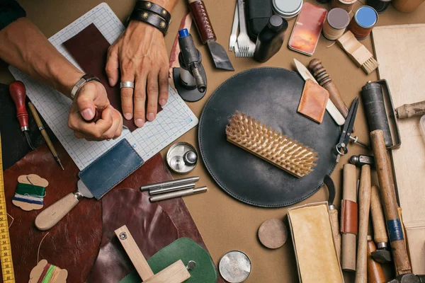 Крупный план сапожника, работающего с кожаным текстилем и молотком в мастерской — стоковое фото