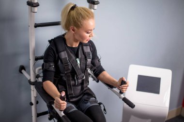çekici sportif kadın Ems cihazın ekrana bakıyor