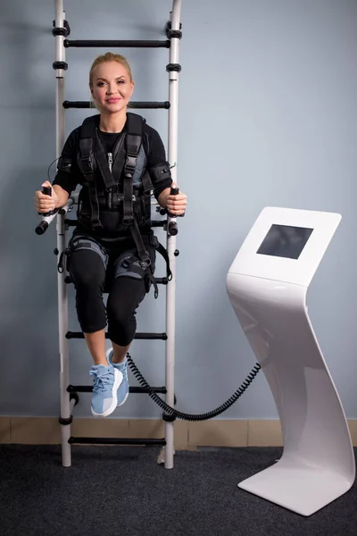 Gut gelaunte Frau sitzt während des Trainings auf der Stange — Stockfoto