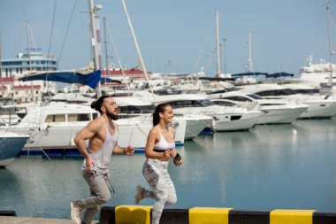 Günbatımında ahşap iskelede koşan genç bir çift.