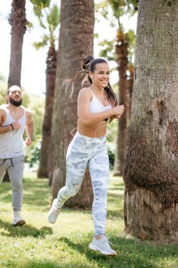 Yaz sabahı parkta koşan genç bir çift.