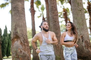 Yaz sabahı parkta koşan genç bir çift.