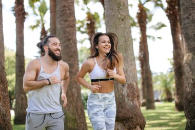 Yaz sabahı parkta koşan genç bir çift.