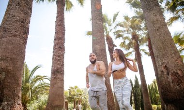 Yaz sabahı parkta koşan genç bir çift.