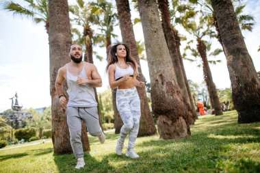 Yaz sabahı parkta koşan genç bir çift.