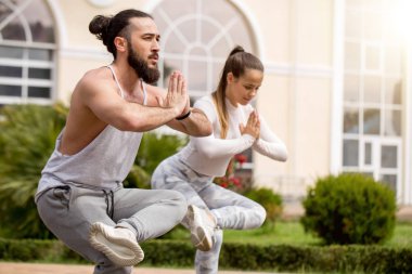 Genç çift dışarıda yoga yapıyor.