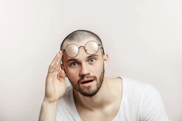 Surpreendido bonito homem levantando os óculos em sua testa no fundo branco . — Fotografia de Stock