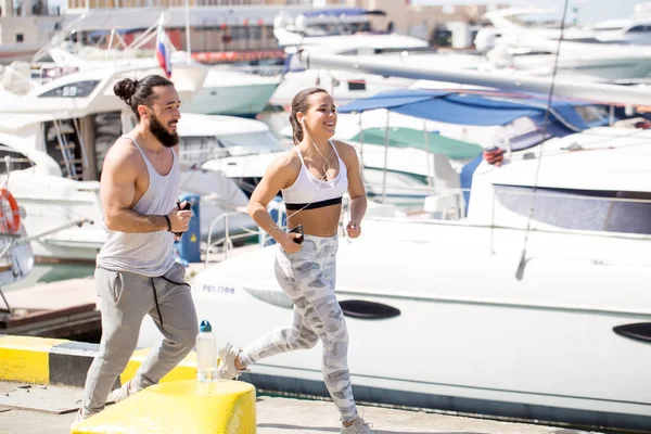 Günbatımında ahşap iskelede koşan genç bir çift.