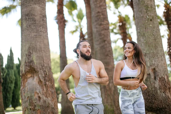 Yaz sabahı parkta koşan genç bir çift.