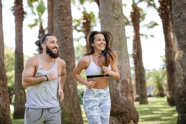 Yaz sabahı parkta koşan genç bir çift.