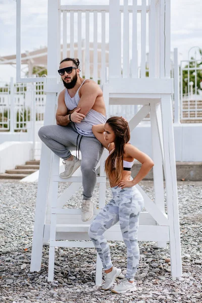 Genç çift, çakıl taşlı plajda dinlenirken kulaklıkla müzik dinliyor.