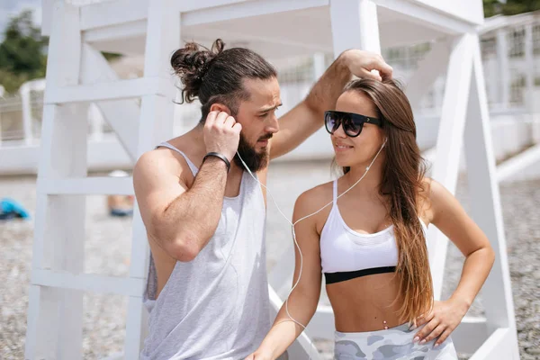Young couple listening to music using one headphones on beach
