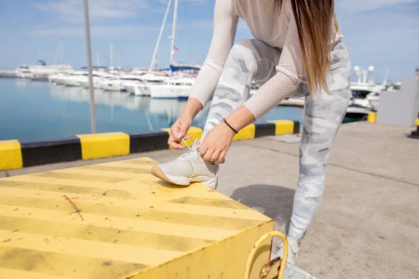Young strong woman in sportswear doing plyometric exercises on pier.